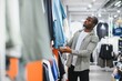 © Serhii - Customer choosing clothes in fashion store, african american man shopping in mall