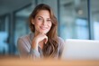 © id512 - Confident smiling businesswoman sitting at desk with laptop in bright modern office working remotely with focus and ease