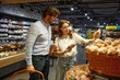 © Nomad_Soul - A man and a woman are examining loaves of bread in a store