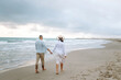 © maxbelchenko - A young couple expecting a child stands on the beach and enjoys the seascape at sunrise. The pregnant woman and her husband spend time together. Concepts of family, love, and nature.