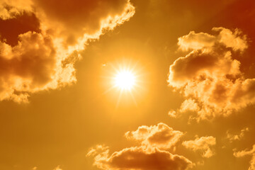 Wall Mural - bright sun and clouds in orange sky during hot summer weather