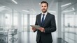 © selawidiani - Portrait of a Confident Businessman Holding a Tablet in a Modern Office