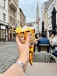 © Ina - Woman hand holding a  Belgian fries in the city center of Brussels. Street food and travel lifestyle moment.