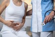 © FARISTABINTA - Worried woman consulting with her doctor about stomach pain and digestive issues