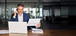 © Stock 4 You - Latin or Indian male business man holding documents, working at laptop computer doing online trade market tech research. Smiling businessman talking phone, check database in office. Banner, copy space