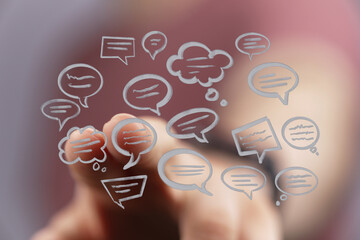 Communication concept. Hand touching digital interface of speech bubbles, representing messages and information flow.