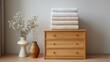 © pinporn manosri - Aesthetic Interior Scene Featuring Wooden Drawer Chest with Neatly Stacked Towels, Decorative Vases, and Minimalist Style for Relaxed Home Environment