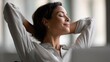 © Chandlerlikes - Smiling businesswoman taking a short break from computer tasks, stretching arms and enjoying a peaceful view outside the window. Workplace wellness and positivity
