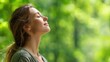 © mila103 - A young woman relaxes outdoors eyes closed and face uplifted taking in the fresh air. Surrounded by green trees she finds tranquility and harmony in nature.