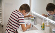 © C&A - Young boy filling a cup with water from the bathroom faucet during his morning hygiene routine