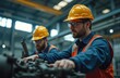 © Vadym - Two men in yellow hard hats, orange safety vests working on machinery in industrial factory. Engineers inspect equipment with safety glasses, blue uniforms. Industrial setting with metal structures,