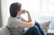 © Maria - Sad girl sits on the sofa at home, problem concept