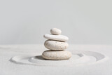 Stack of spa stones on light sand against grey wall. Zen concept