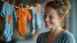 © SSP - Joyful expecting mother hanging cute onesies at home lifestyle photography warm indoor environment close-up view