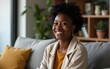© wang - people, race, ethnicity and portrait concept - happy african american young woman sitting on sofa at home. High quality