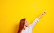 © wang - Redhead woman over isolated yellow background pointing finger to the side. High quality