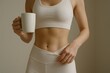 © Gibster - Wellbeing program work. A woman in activewear holding a mug, showcasing a fit midsection.