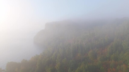 Wall Mural - A thick morning fog blankets Lake Superior’s cliffs and forests, as early autumn colors emerge along Ontario’s rugged shoreline