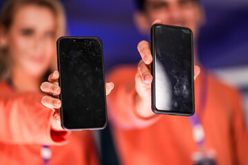 Two app developers showcase their new product on mobile phones. The blank screens provide a perfect template for marketing agencies to add a custom user interface for a new app launch.