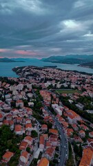 Wall Mural - Aerial drone flies over eastern Dubrovnik, capturing mountains, trees, and the Adriatic Sea glowing warmly in golden light during a calm autumn sunset along the scenic Croatian coastline.