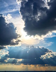 Wall Mural - Beautiful summer clouds float high in the blue sky over the sea, catching the bright sunlight