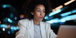 © Andrii Zastrozhnov - Focused african female adult working on laptop at night with city lights