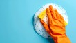© its.myillusions - A detailed view of a hand in a vibrant orange cleaning glove, using a soapy yellow sponge to wash a smooth blue surface