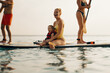 © Jacob Lund - Mother and child enjoying stand-up paddleboarding on the calm ocean waters