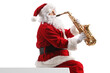 © Ljupco Smokovski - Santa claus sitting on a wall and playing a saxophone