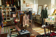 © pressmaster - Vintage thrift shop interior featuring racks of assorted clothing, accessories, musical instruments, vinyl records, and sustainable fashion signage arranged in eclectic retail space