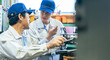 © metamorworks - A group of male workers operating machines in a factory