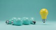 © MAMUNURRASHID - Yellow light bulb floats above teal light bulbs on teal background blue idea