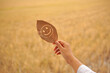 © tuan12 - Smiley face carved on a dried leaf held by a female hand with warm and earthy background, showing calmness, mindfulness, and creativity.