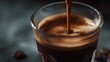 © Thares2020 - Close up of rich dark espresso being poured into a clear glass creating a frothy crema