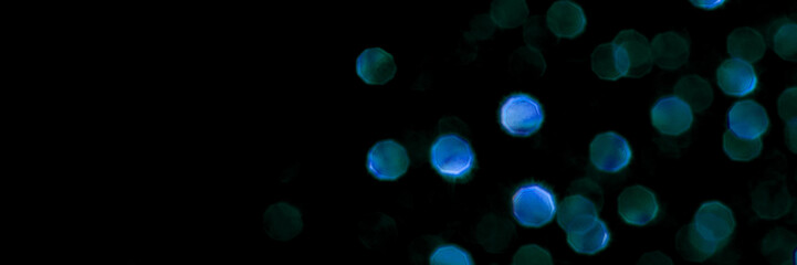Dark blue and green bokeh lights against black background creating a dreamy aesthetic atmosphere.