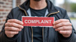 © DreamyDesignsCo - Man presenting complaint card, symbolizing customer service challenges and feedback, useful for business analysis and conflict resolution discussions