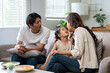 © amnaj - Asian parents and young daughter sitting on sofa at home, enjoying talking and spending quality time together