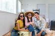 © amnaj - Asian parents and daughter wearing sunglasses and a straw hat, sitting with luggage, excited for an upcoming trip