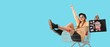 © Pixel-Shot - Happy young woman with shopping bag sitting in cart on blue background with space for text. Black Friday sale