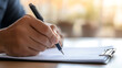 © photo for everything - Hand writes on paper with a pen in bright light. Business or educational document concept. Close-up shot of signing paperwork on a clipboard.
