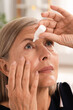 © New Africa - Senior woman applying eye drops at home