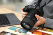 © New Africa - Professional photographer with camera working at wooden table in studio, closeup