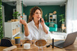© Miljan Živković - Woman multitasking working from home, talking on phone, applying makeup