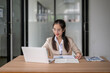© Wasana - Asian businesswoman working with laptop and documents at office desk