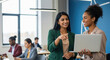 © PRASANNAPIX - Diverse businesswomen collaborating on a laptop in a modern office.