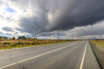 Wall Mural - Road with a cloudy sky above it
