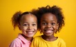 © liang - Close up portrait of two cute african american little girls smiling and looking at camera isolated on yellow background. Happy siblings day. High quality