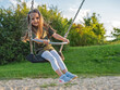 © Razbitnov - Happy toddler girl enjoying sunny day on a swing in the park, childhood joy and outdoor fun in autumn light
