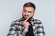 © bodnarphoto - Man looking thoughtful with hand on chin and a slightly skeptical expression in a neutral background setting
