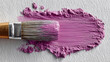 © Nataliya - A brush with a stroke of light purple paint symbolizing art and renewal, with space for text.